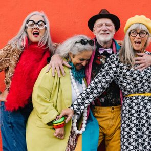 Vibrant senior citizens having fun against a red background