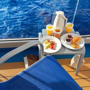 A colorful continental breakfast served on a balcony of a cruise ship at sea, with fruit, juice, breads and coffee.