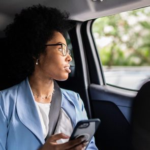 Businesswoman using smartphone and looking though a window in an uber