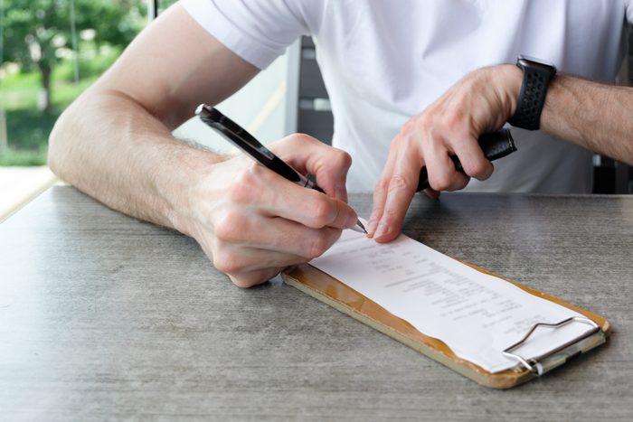 Man Signs Credit Card Receipt at Restaurant