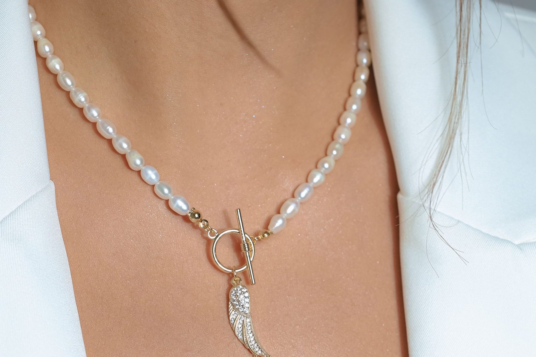 Closeup shot of a key pearl necklace worn by a Caucasian female.