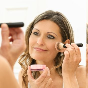 Beautiful 40s woman applying makeup