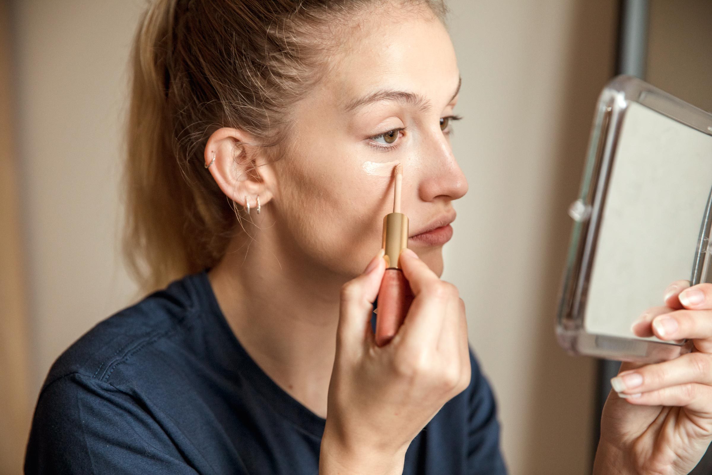 woman applying concealer under her eyes