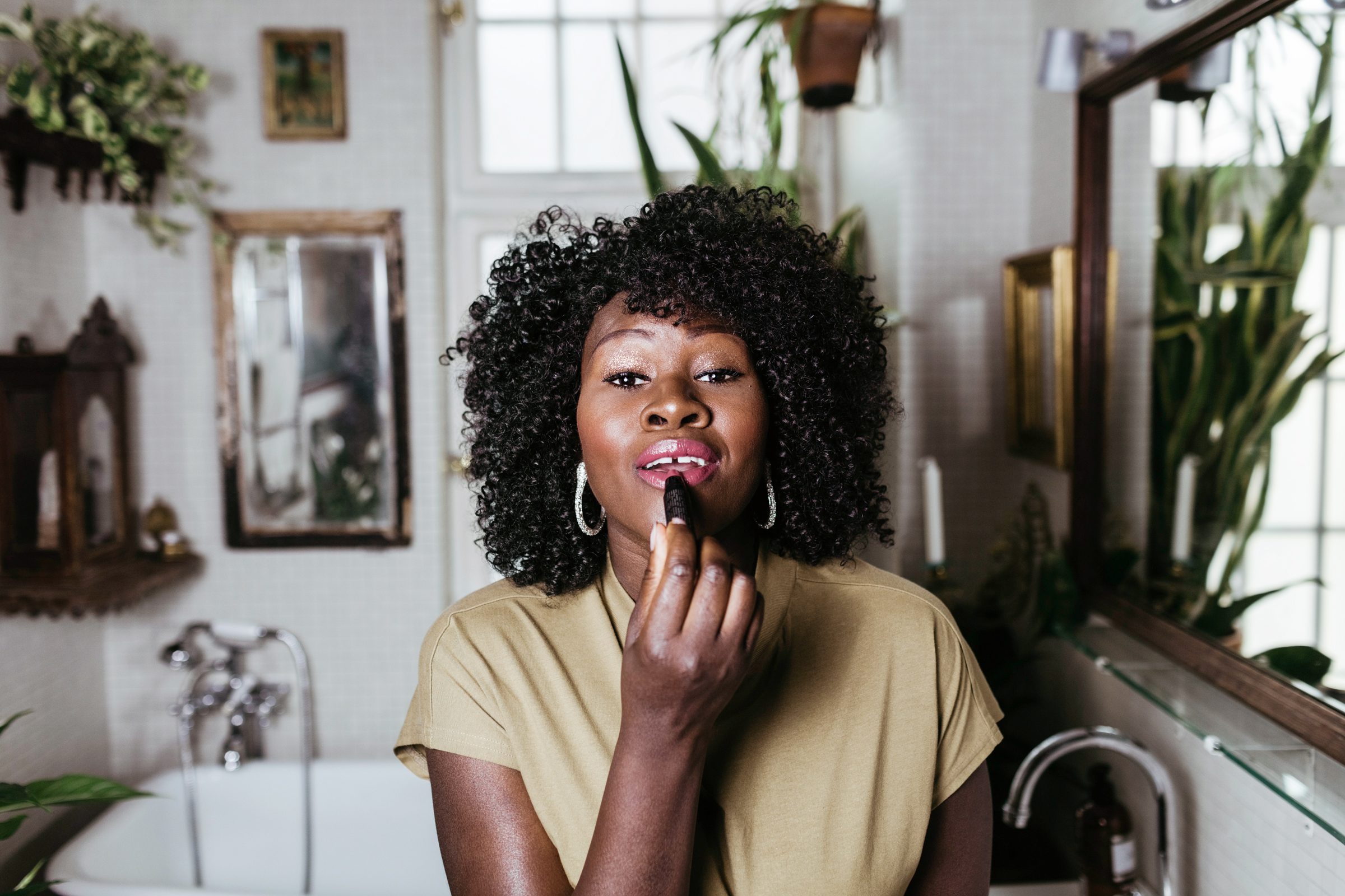 Portrait of mature female make-up artist applying lipstick in bathroom at home