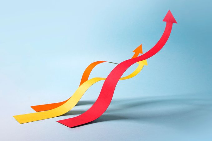 Three wavy paper arrow chart lines moving upwards to one direction on blue background.