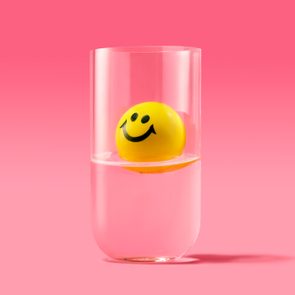 Yellow smiley face floating in a glass half full of water