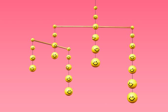 mobile made up of yellow smiley faces on pink background to represent community and support network for a happier life