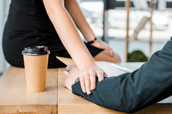 cropped shot of businesswoman flirting with colleague at workplace in office