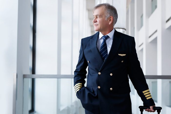 Experienced senior pilot pulling his luggage in the airport terminal