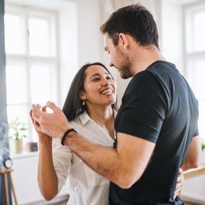 Affectionate young couple in love dancing at home, having fun.