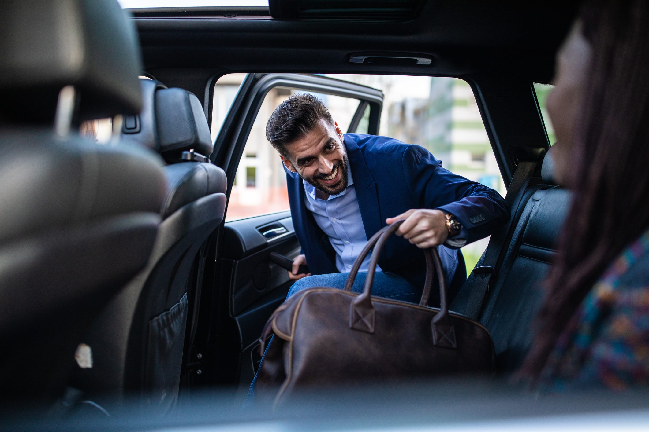 Good-looking man entering ride sharing car