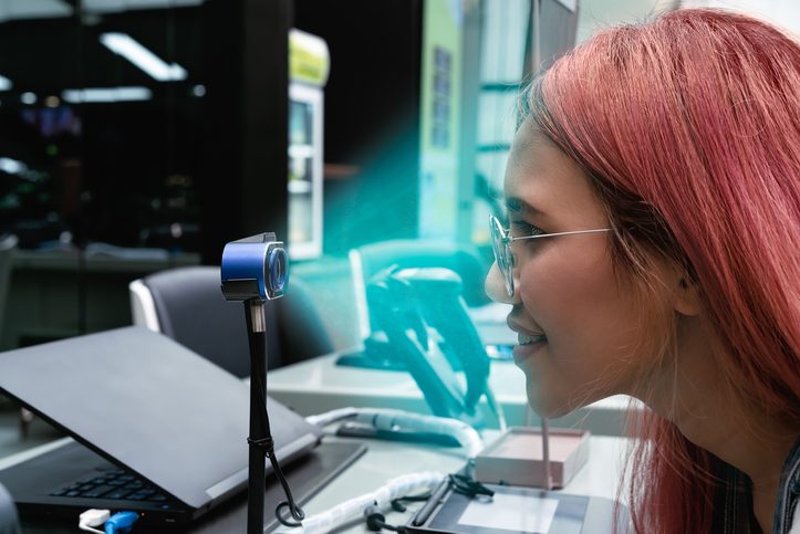 Young woman using digital biometric identification facial scanner to authorise cashless payment at retail store