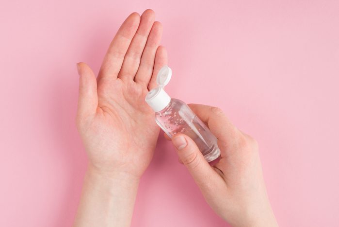 Top above overhead close up pov first person view photo of female applying gel sanitizer to her hands isolated on pink pastel background with copyspace