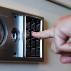 Blurred safe with combination lock and human hand in a hotel room