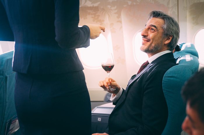 Cabin crew serving food to passenger of business class in airplane