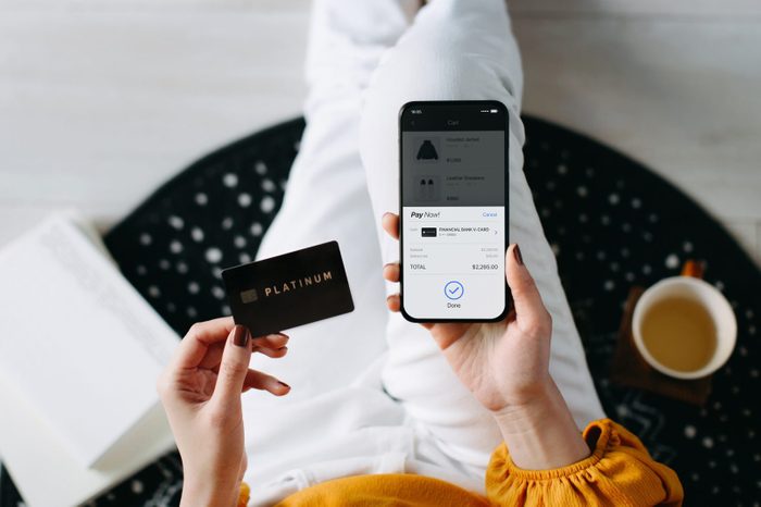 Overhead view of young Asian woman relaxing at home, shopping online with smartphone and making payment online with credit card on hand. Lifestyle and technology. Contactless payment. Comfortable and fast shopping experience