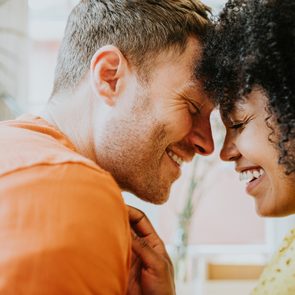 An interracial couple tenderly touch foreheads together and giggle