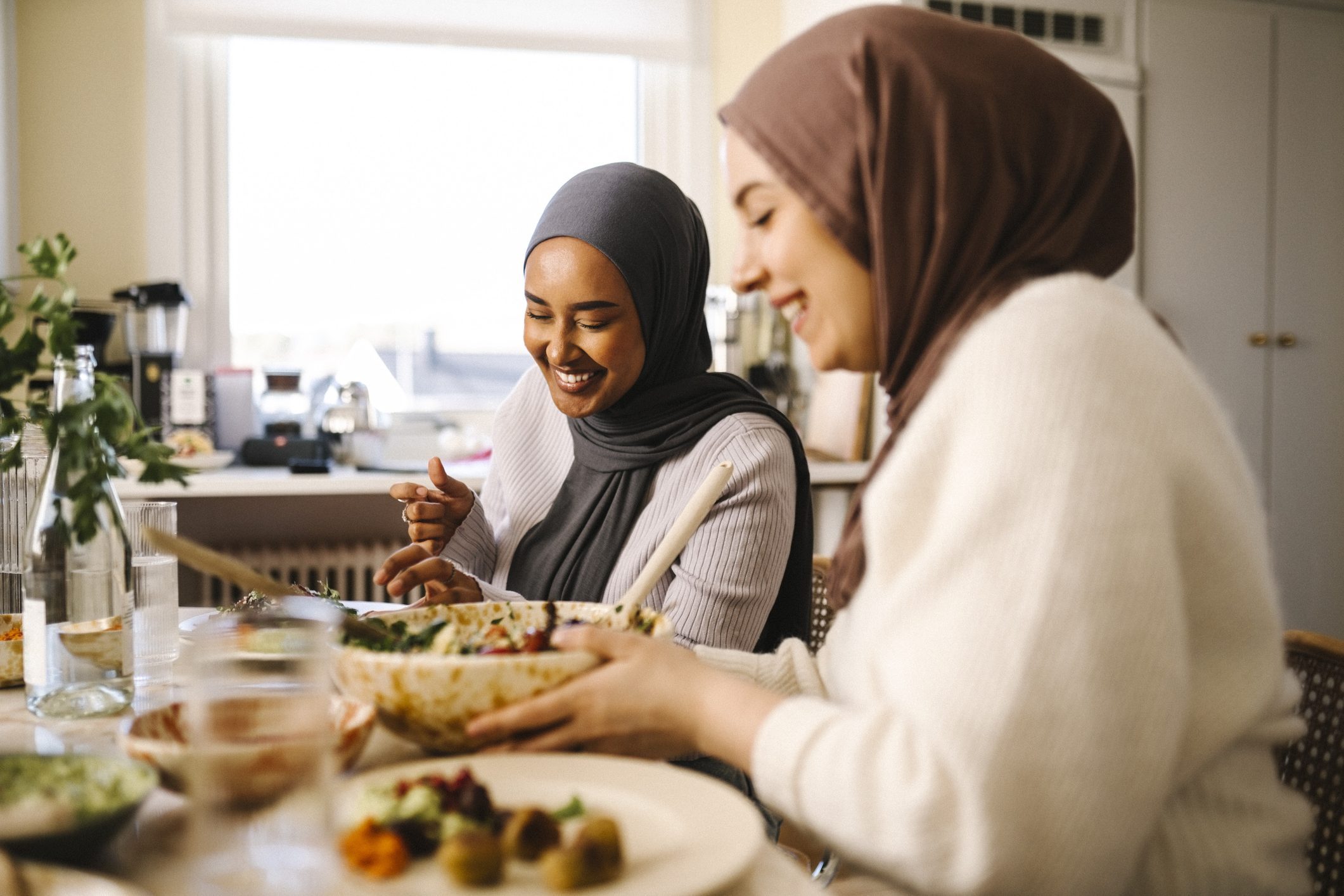 Smiling young woman sitting with friend at dining table