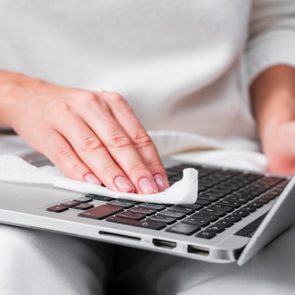 Midsection Of Woman Cleaning laptop keyboard with a cleaning cloth