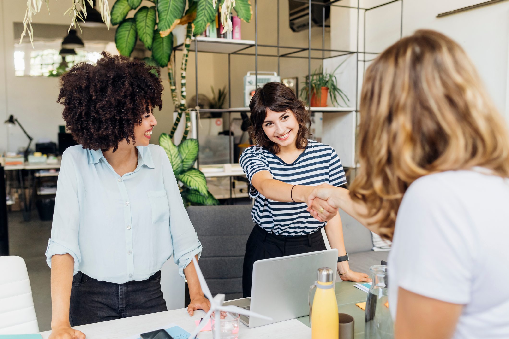 Smiling colleague shaking hand with manager at office