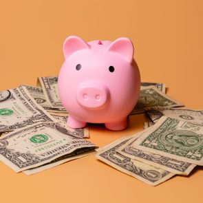 A piggy bank with US dollar bills isolated on an orange color background in studio photo. Finance and economy concept.