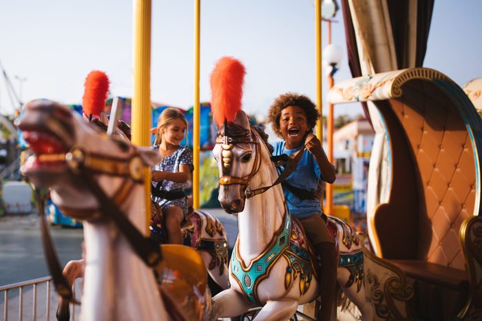 Multi-ethnic children having fun on funfair merry-go-round carousel ride