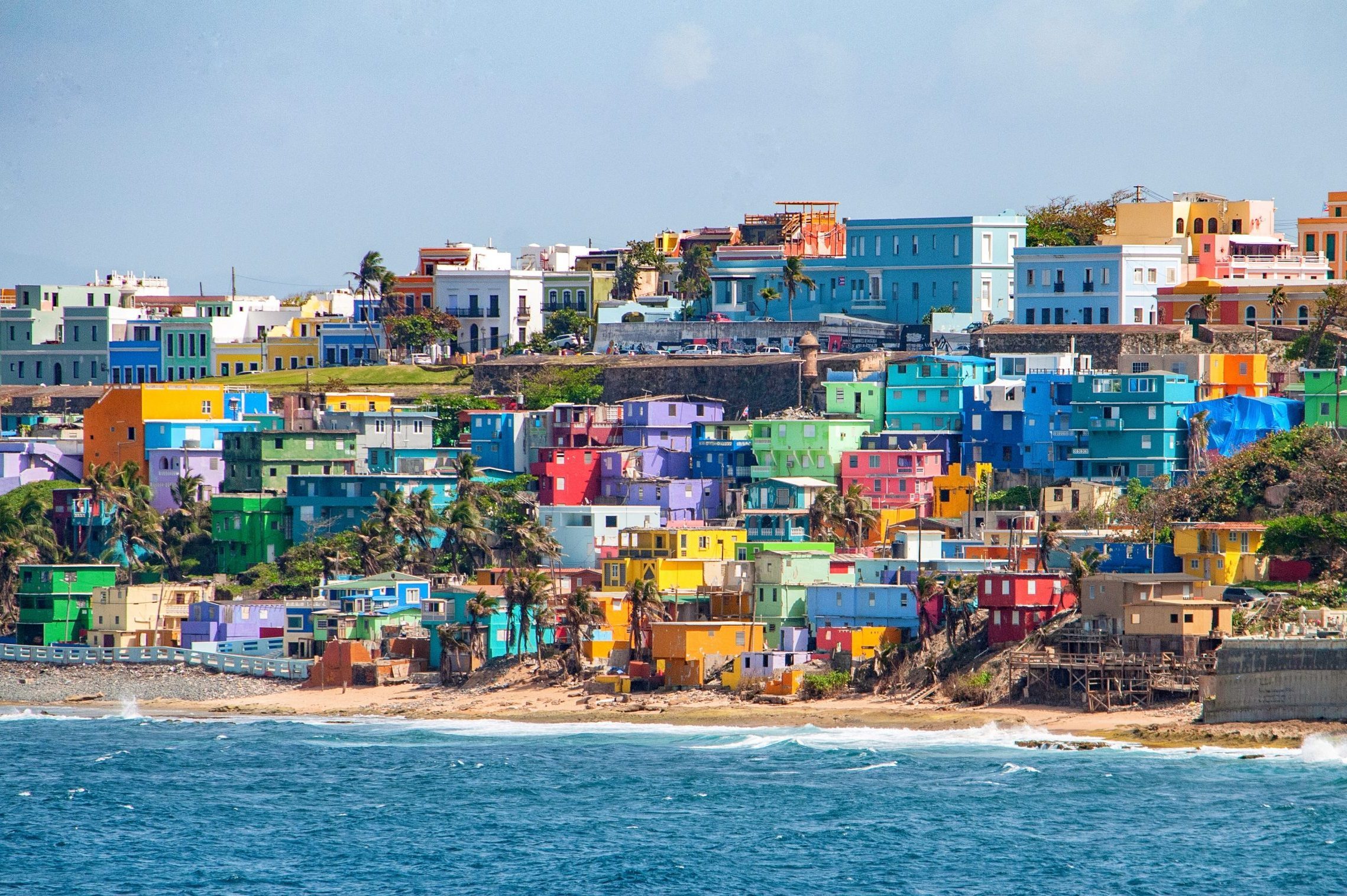 Bright colorful houses line the hills overlooking the beach in San Juan, Puerto Rico