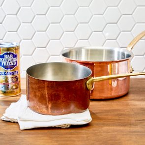 copper pots showing before and after cleaning; some cleaning supplies nearby