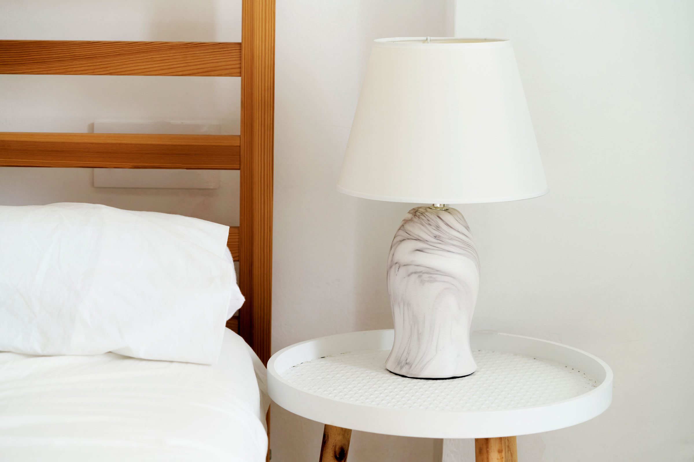 close-up of white lamp on bedside table inside a white walled room.