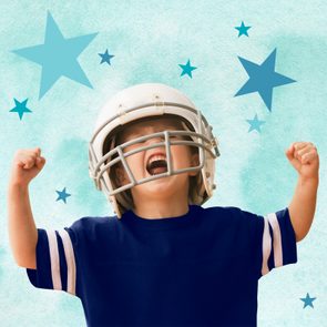 Boy wearing a football helmet cheering with fists clenched