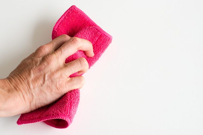 Cropped Hand Cleaning White Wall With Napkin