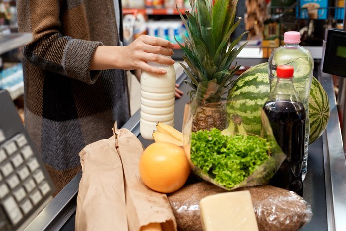 Young adult woman putting food on checkout desk