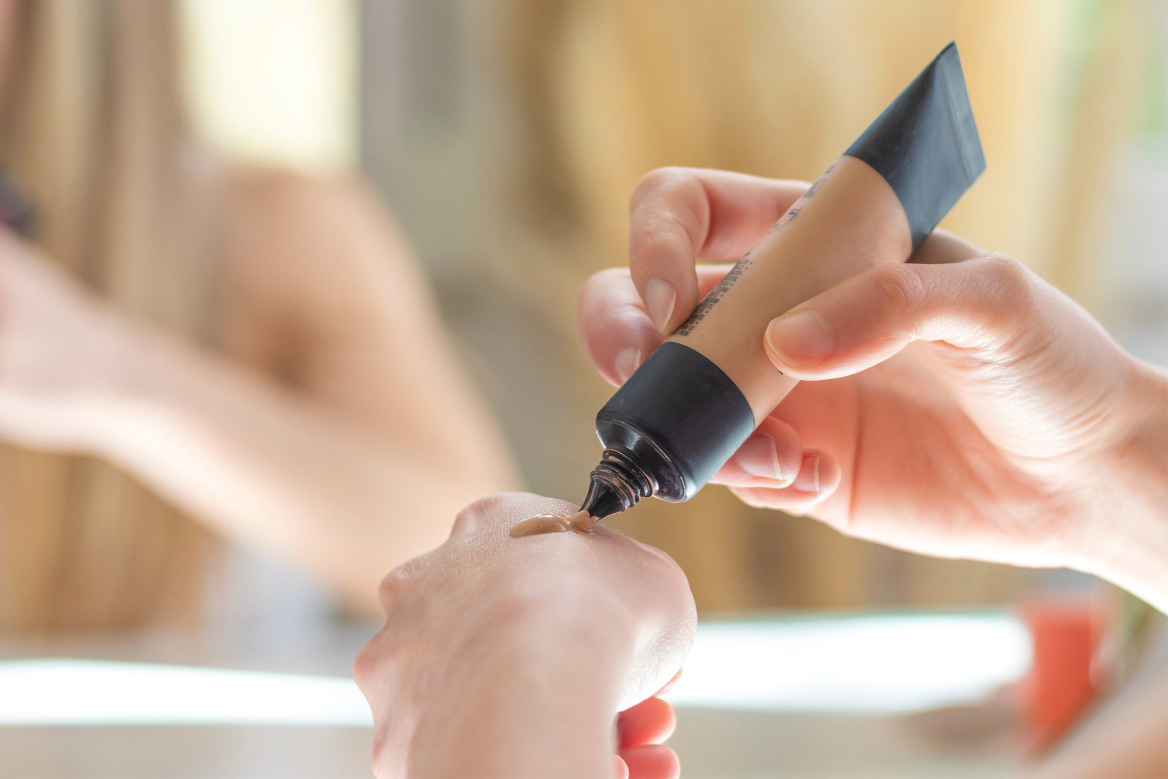 Woman squeezing foundation tube onto hand