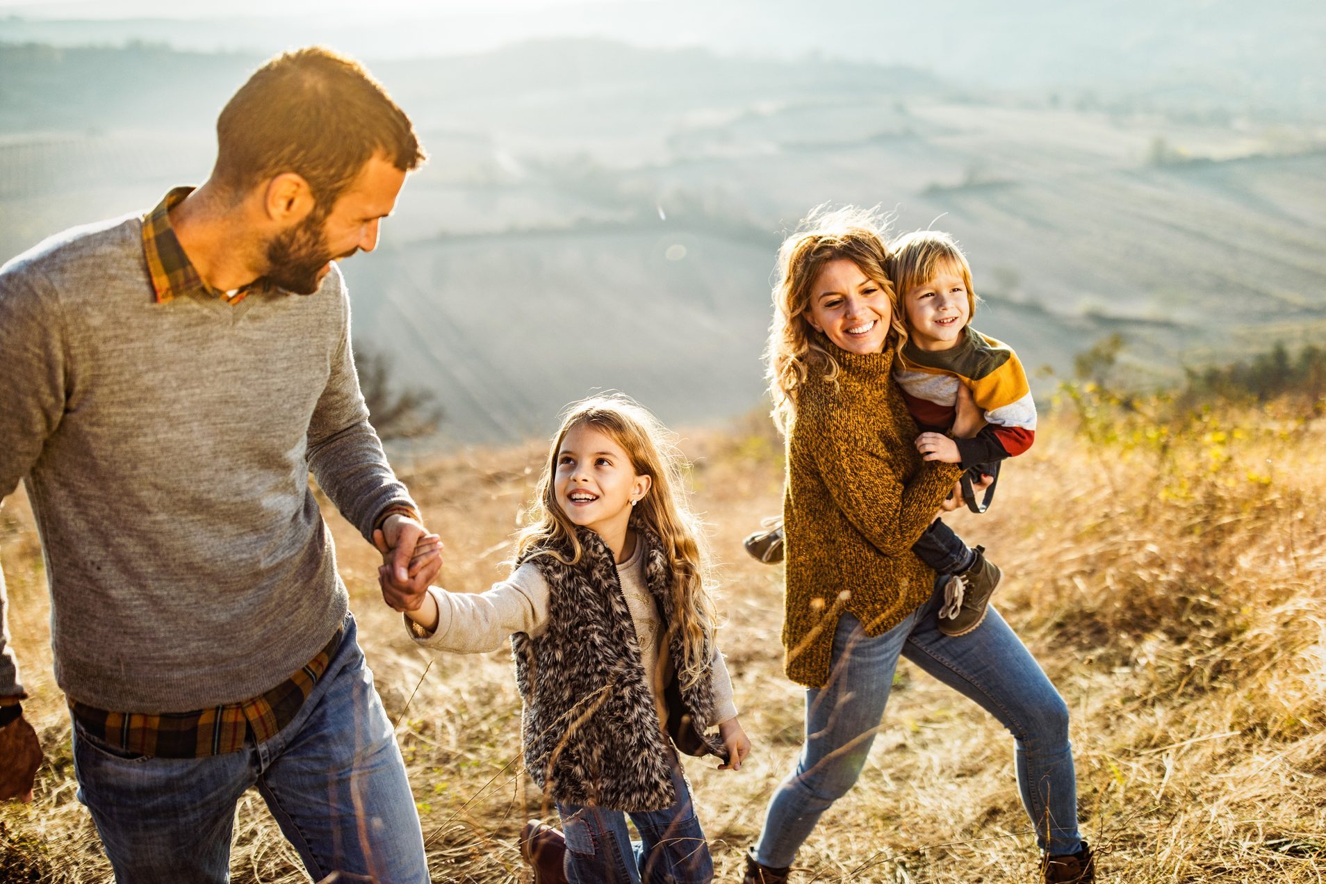 Happy family enjoying while walking up the hill in autumn day.