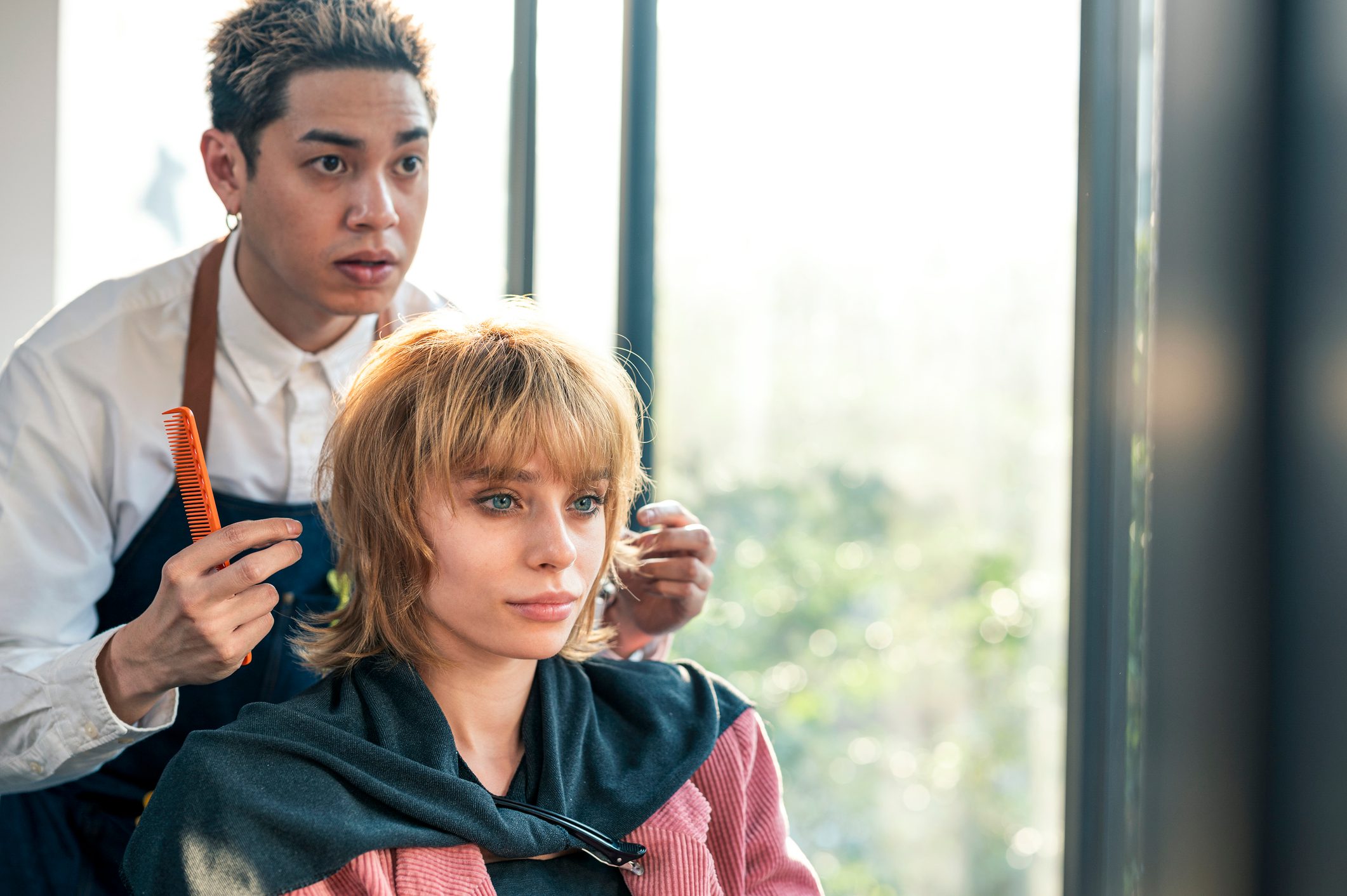 Asian hairdresser owner is giving advice about hairstyle to his customer at hair salon.