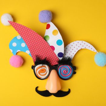 Funny face made of party items on yellow background, flat lay. April Fool's Day