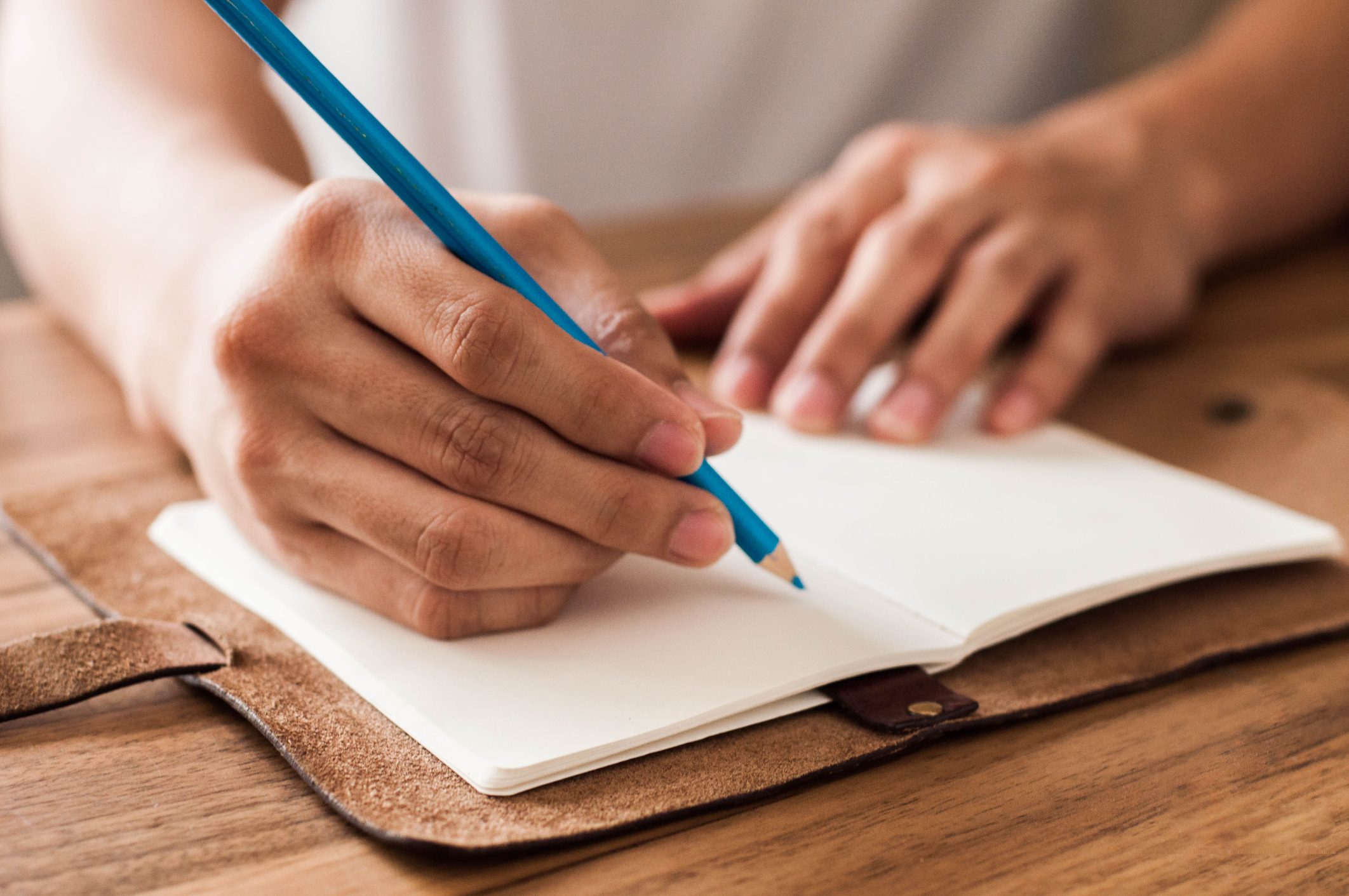 Close-up view of a Southeast Asian man writing on a journal