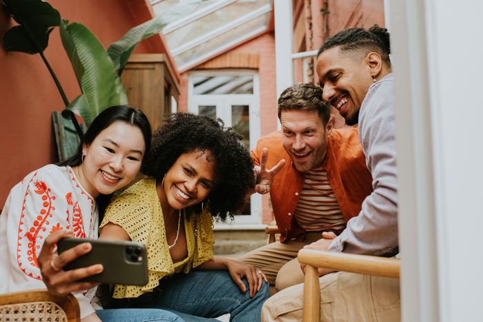 A group of 4 young people take a selfie on a mobile smart phone