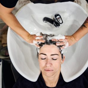 Hairdresser lathers client's hair.