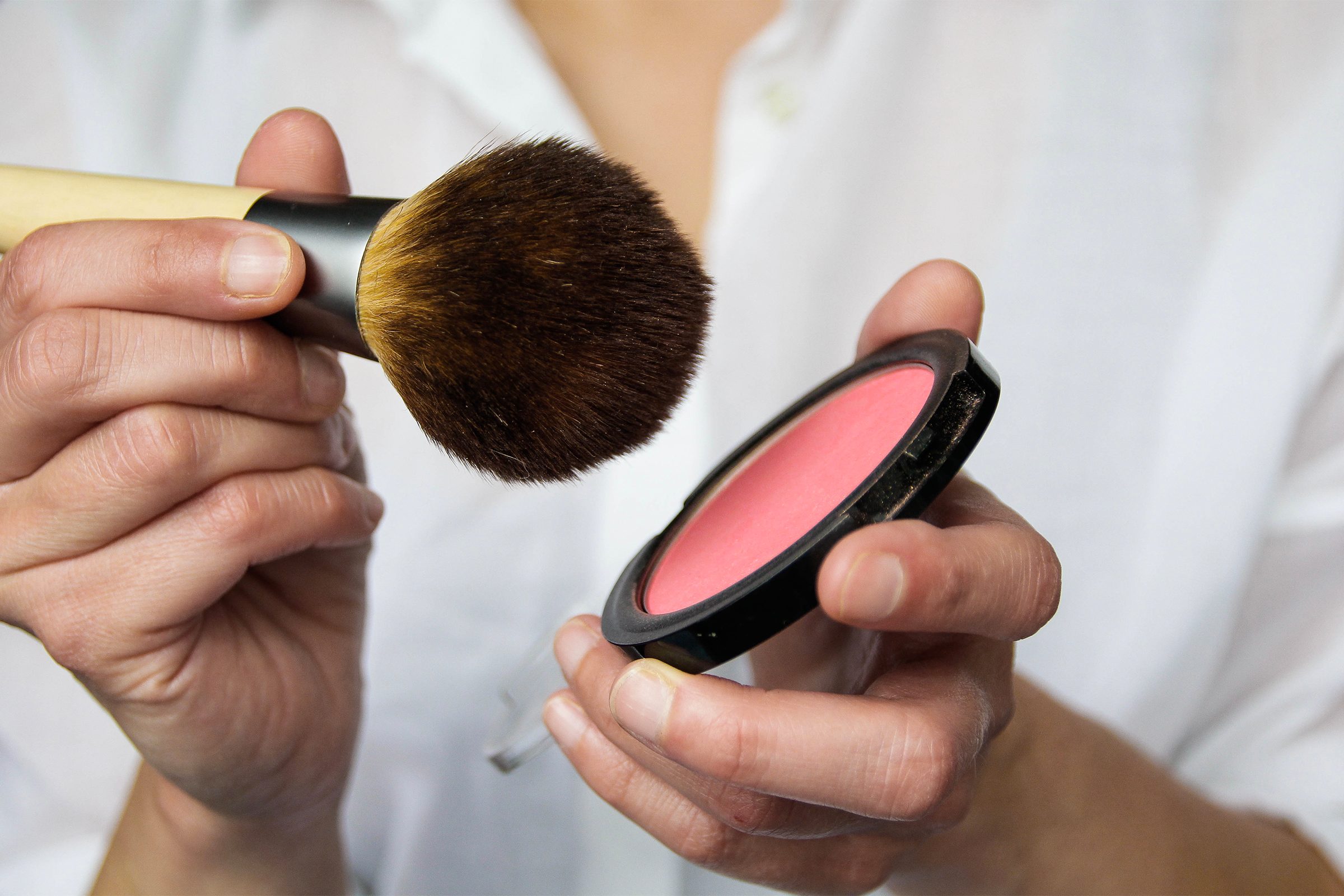 Close up of woman holding blush and makeup brush