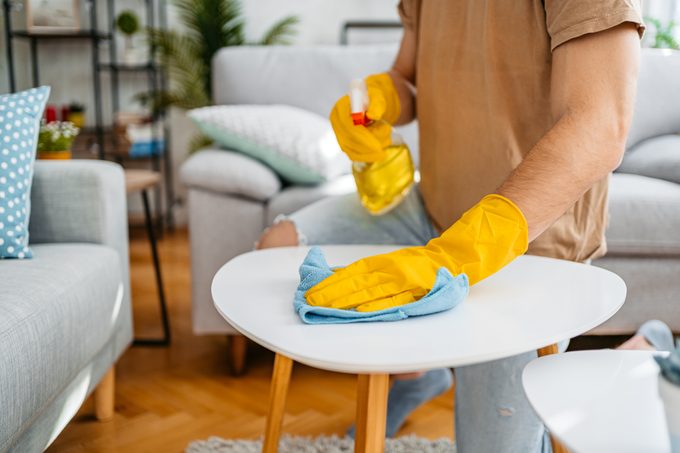 Young Man Cleaning His Coffee Table At Home