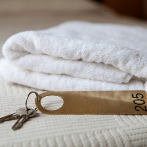 Close up of a hotel room with keys on a comforter bedspread