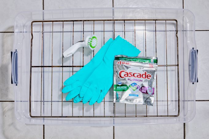 oven rack and cleaning supplies laid out in a plastic tub