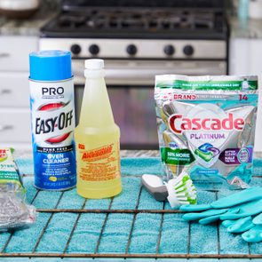 oven rack and cleaning supplies arranged on kitchen counter with an oven seen in the background
