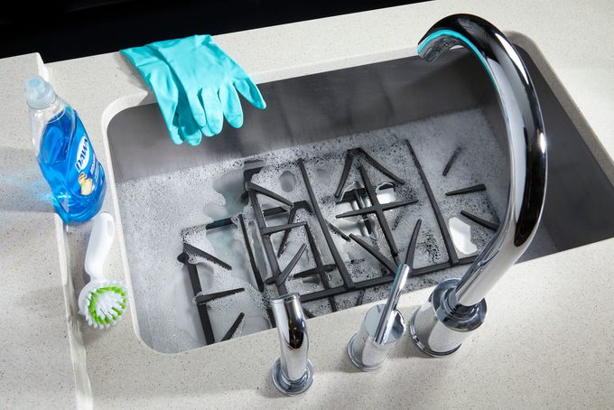 Gas Stove Top grates soaking in a kitchen sink