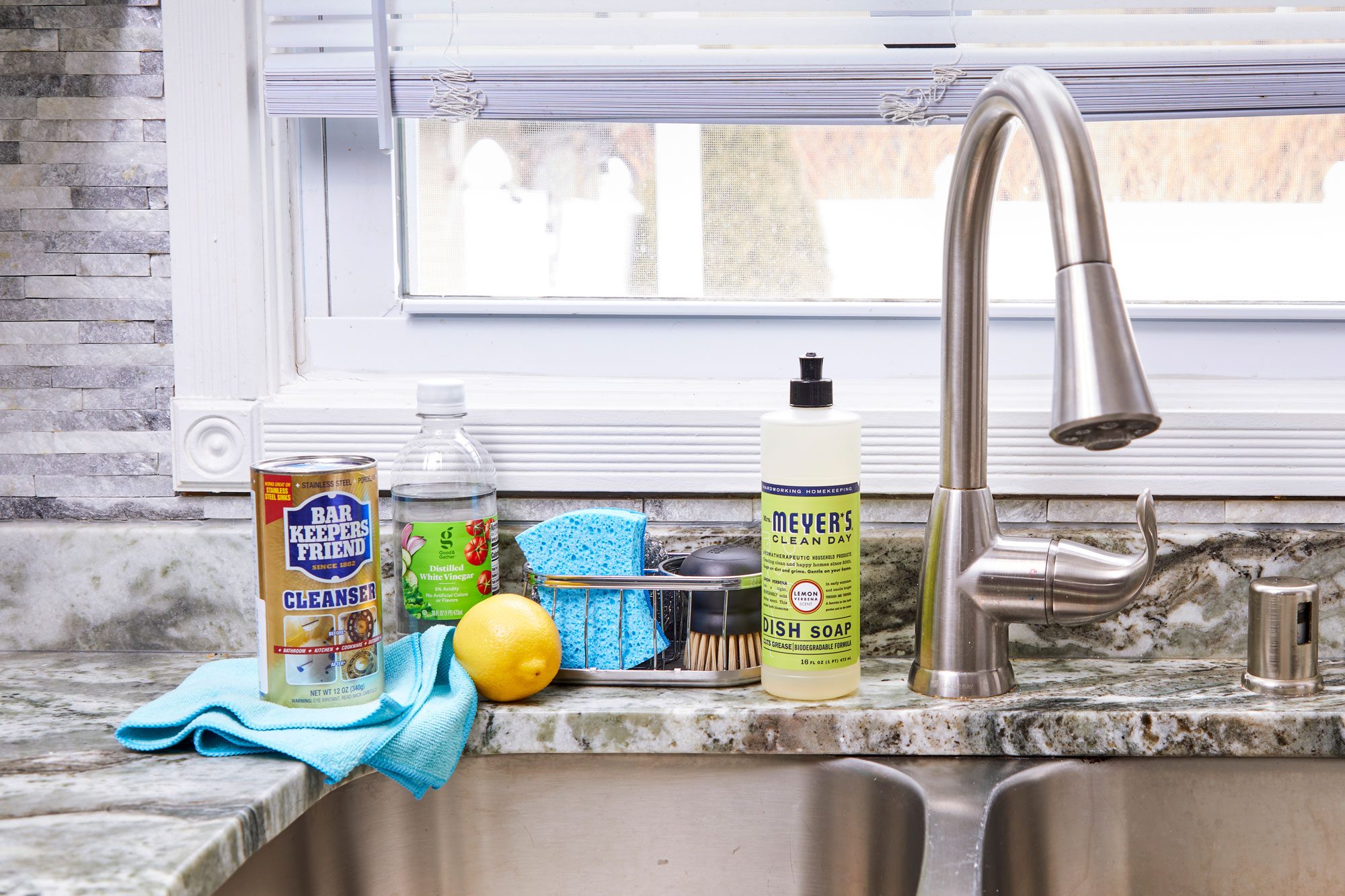 cleaning supplies gathered near stainless steel kitchen sink