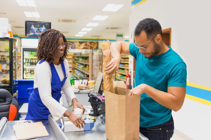 man checking out at the grocery store and bagging his own groceries