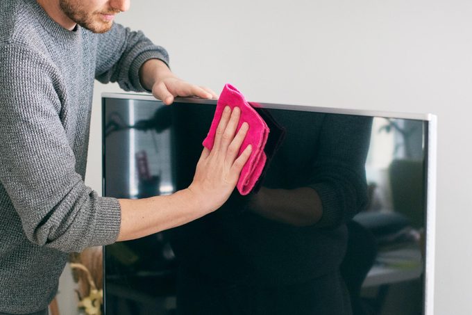 man dusting TV with a micro fiber cloth