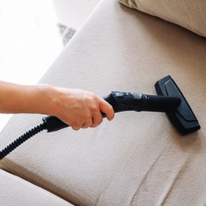 Hand cleaning a sofa with steam cleaner, Home cleaning concept.