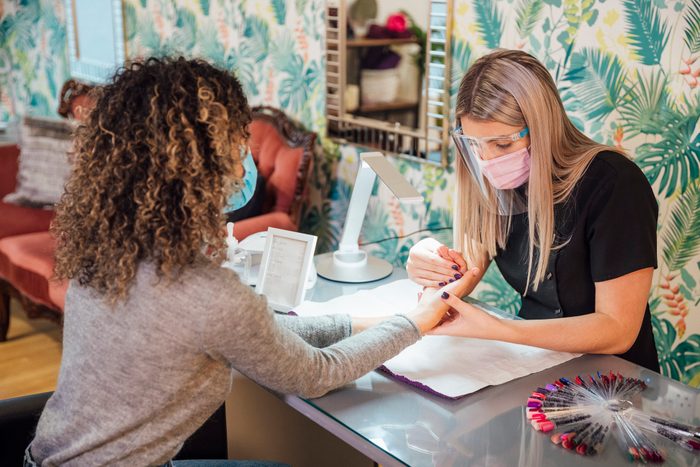 And over the shoulder view of a female nail technician giving a manicure to a client